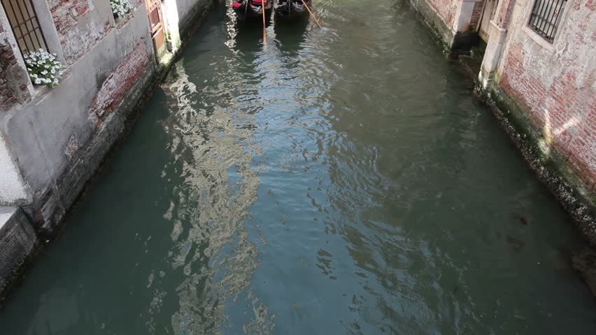 VENICE, ITALY MAY 28 2011: Gondola on narrow canal between ancient buildings with a couple enjoying the cruise in Venice. Economic boost to troubled European country and Euro currency.