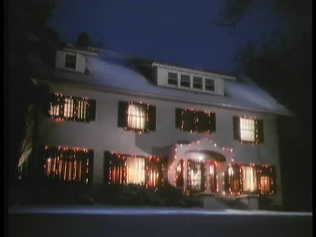 Establishing shot of full moon hovering over house decorated in Christmas lights