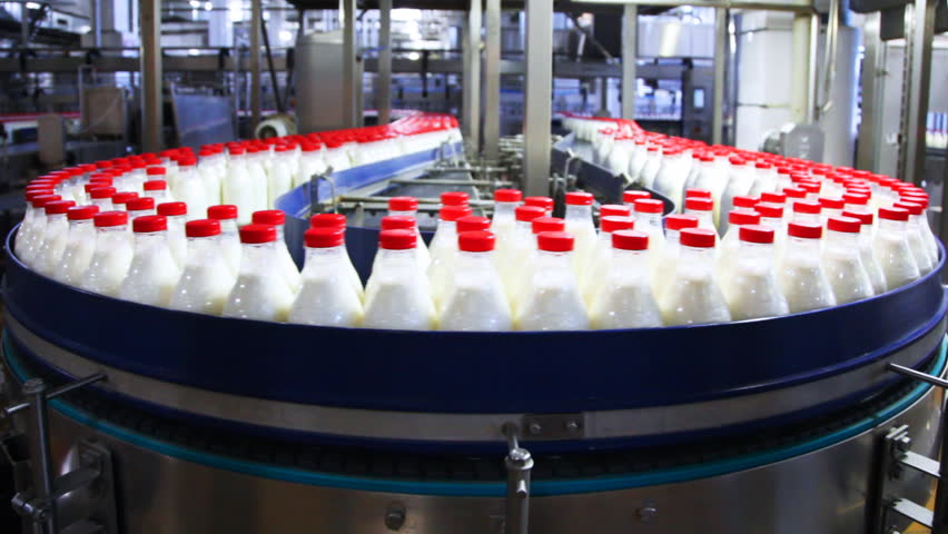 lots of plastic bottles with milk and red caps at factory moves in circle