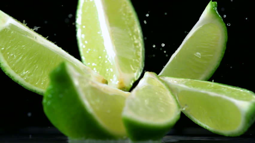 Slo-motion lime  falling into wedges against black drop