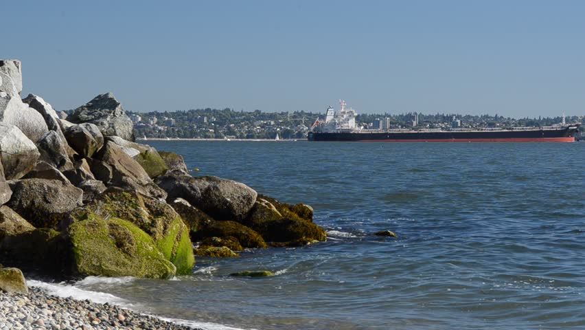 Large cargo ship in pacific ocean over rocky beach near Vancouver, Canada.