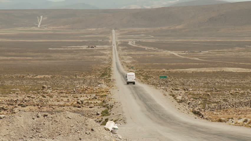 Car driving down desert road in the Andes