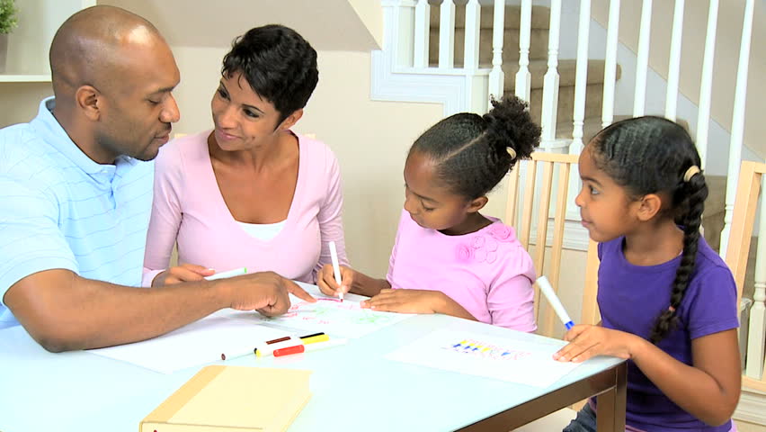 Young african american parents watching their cute young daughters using coloring crayons