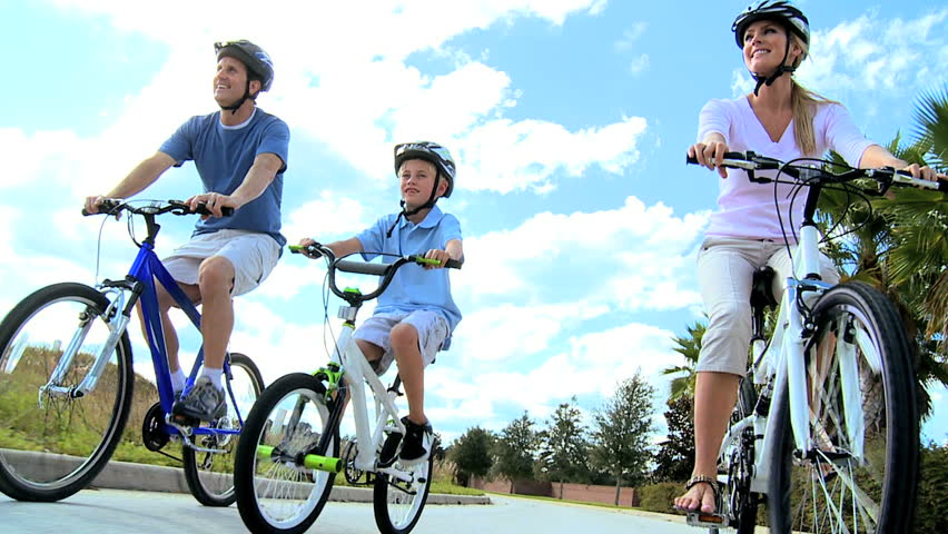 Healthy young caucasian family outdoors together riding their bicycles