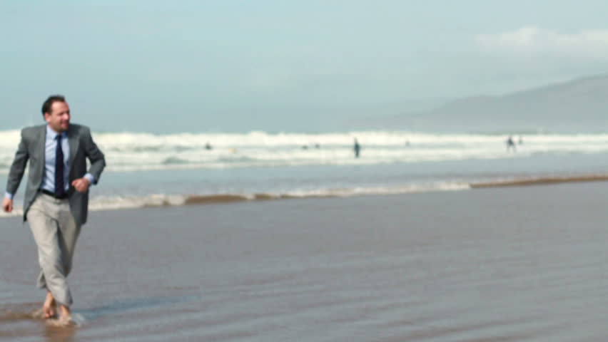 Excited businessman screaming and raising hands to the sky by the sea, slow motion