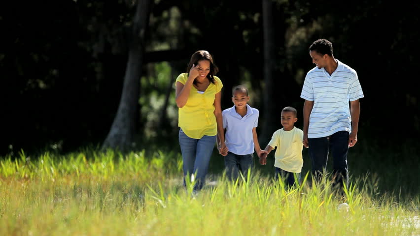 Young african american family jogging together through parkland
