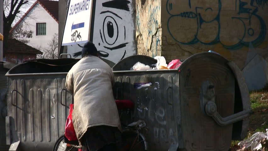 ZRENJANIN, SERBIA -  JANUARY 2012 - Hungry person collects food from rubbish bins circa January 2012 in Zrenjanin, Serbia.