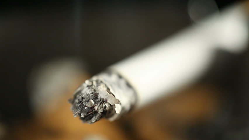 Burning cigarette with smoke in ashtray
