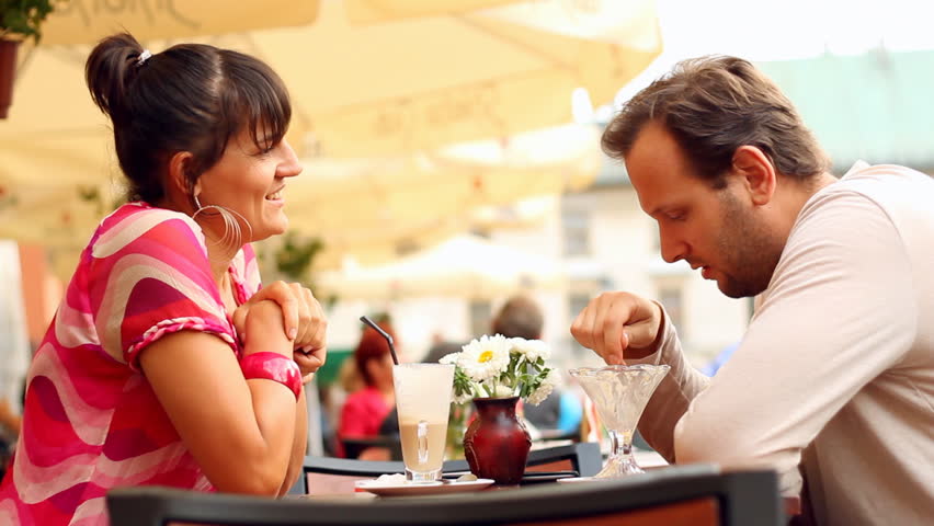 Happy young couple talking in restaurant, outdoors, steadycam shot
