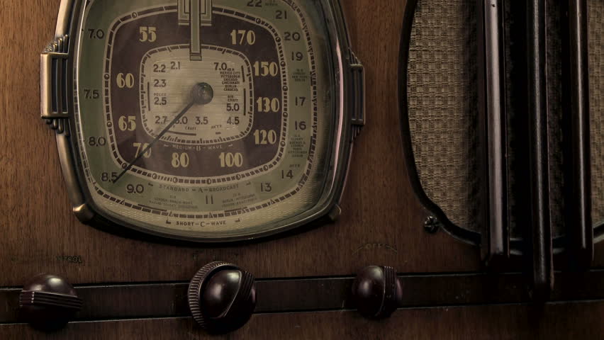 Female hand turning on and tuning a antique radio