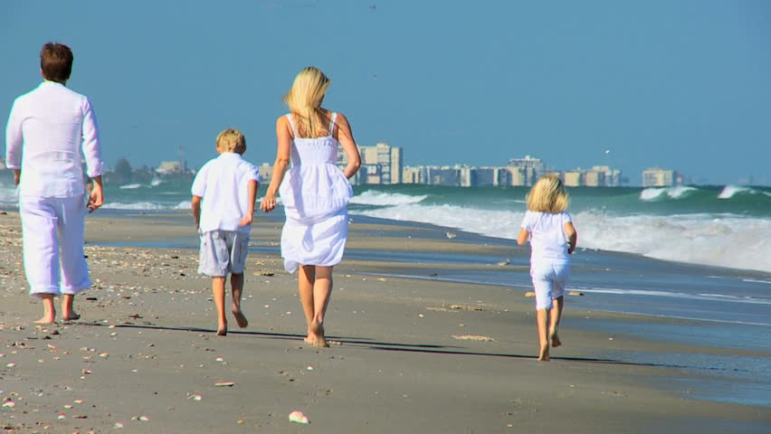 Young children having fun running by parents on the beach