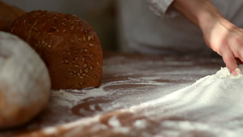 Baker mixing egg with flour on table, slow motion, dolly shot 