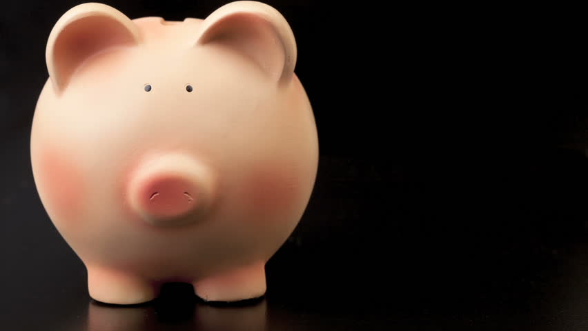 stacking coins next to piggybank