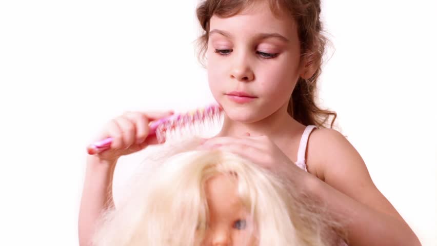 Little girl combs dolls hair, isolated on white background