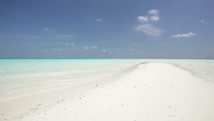 woman in white bikini with flippers running on sandbar
