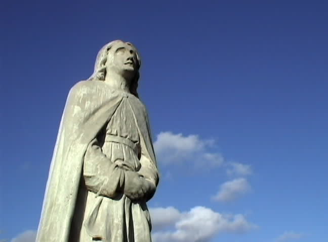 clouds pass behind a religious statue