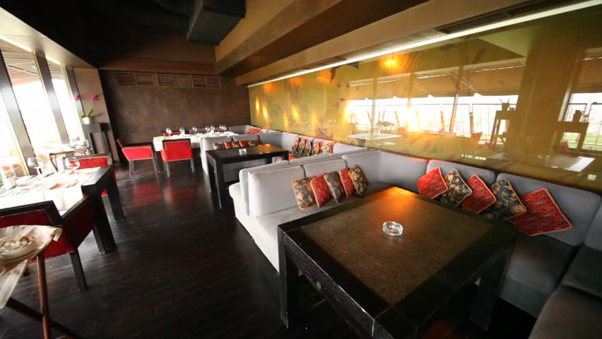 Restaurant lounge is filled by table of black color and by sofas with color throw pillows