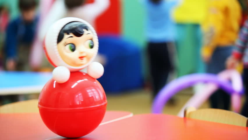 roly-poly toy wobbles on table, in defocus behind it children play