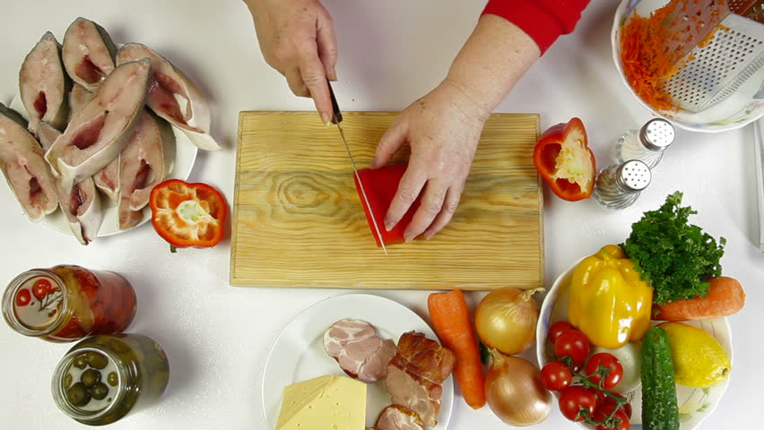 Female hands cooking ingredients for baked fish - chopping bell pepper. Shoot from above