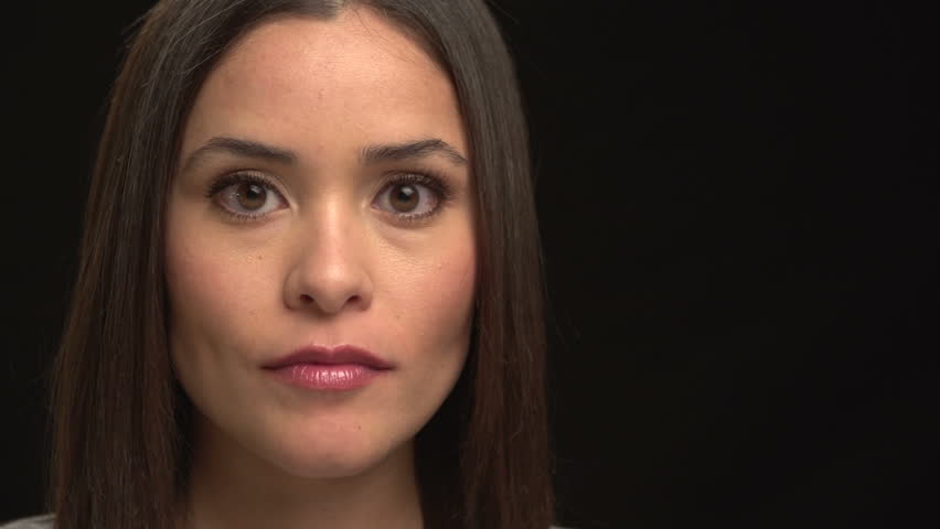 Close up of woman's face on black, serious then smiling