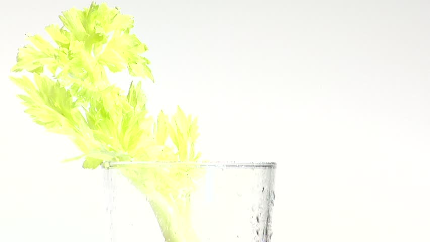 Pouring tomato juice into a glass with a stick of celery