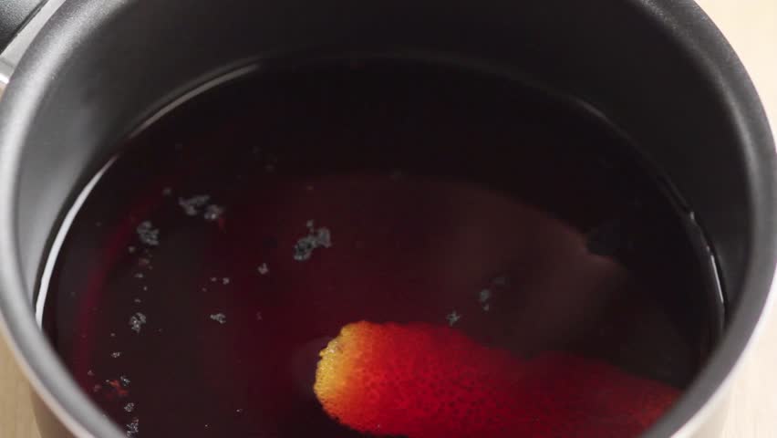 Berry juice being seasoned with orange peel, vanilla seeds and cinnamon