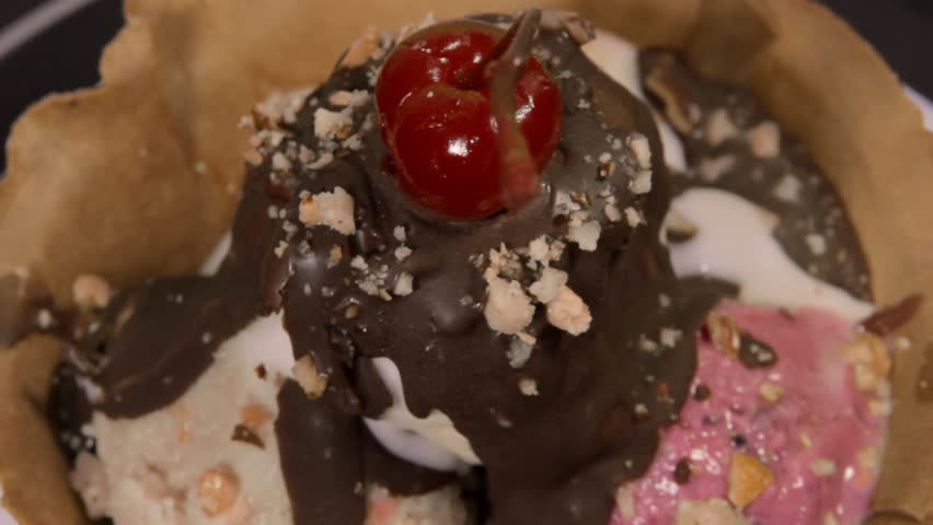 Ice Cream Rotating Close Up (HD). Chocolate drenched three flavor ice cream sundae with cherry rotating in close up.
