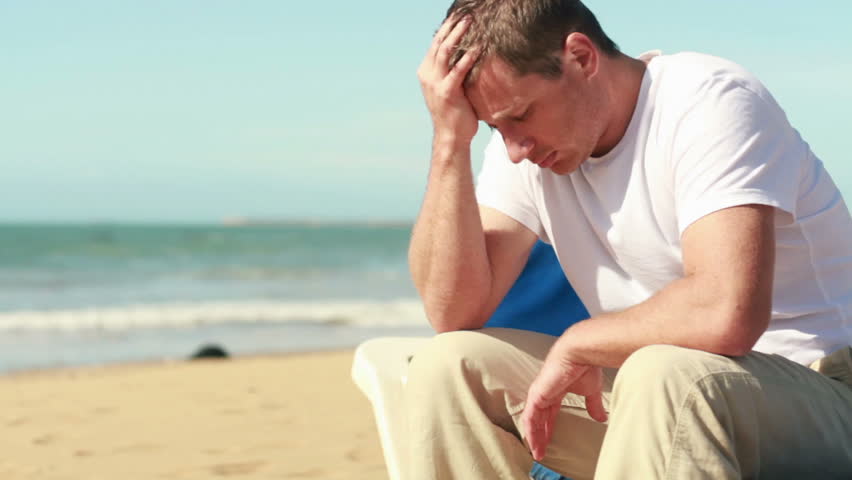 Sad man sitting on sunbed by the sea, steadicam shot

