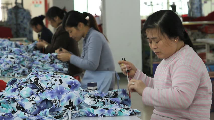 SHENZHEN, CHINA -  JUNE 5: Chinese Woman re-threads sewing machine to sew on zippers. June 5, 2011 in Shenzhen, China
