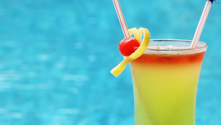 Cocktail in a glass with a tubule against blue water Sex on the beach.