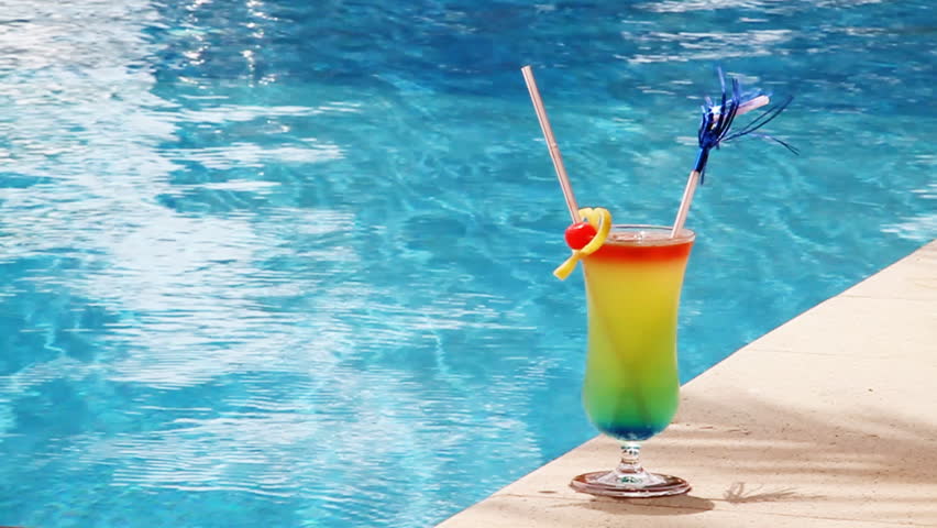 Cocktail in a glass with a tubule against blue water Sex on the beach.