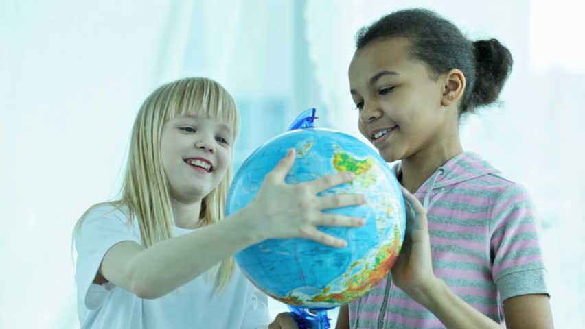 Two schoolgirls spinning the globe and choosing playfully the destination