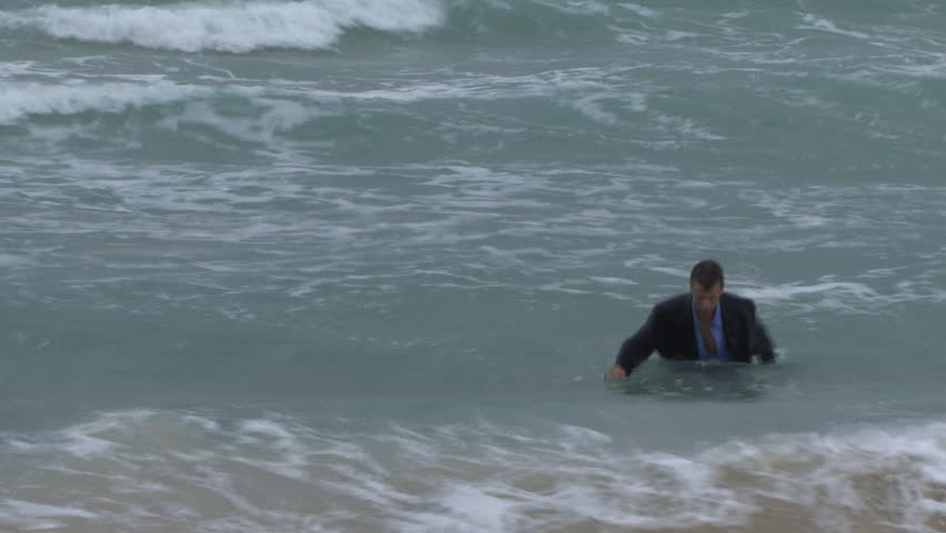 Male walking out of the ocean in suit