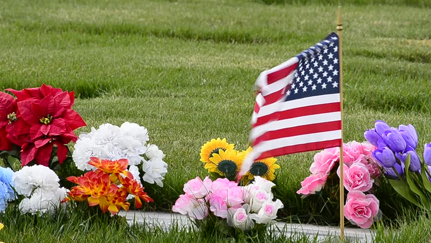 Flag and Flowers blowing in breeze at cemetery plot