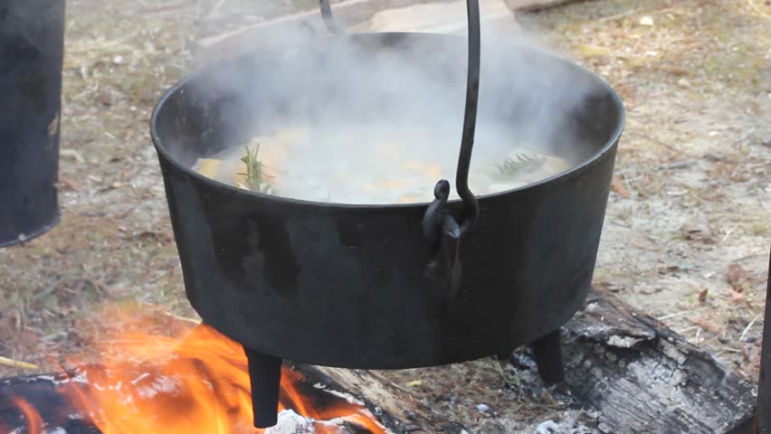Cast Iron Pot  With Food Swinging Over Fire And Boiling