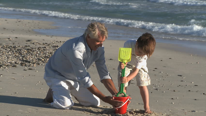LONG SHOT OF A GRANDFATHER AND GRANDSON MAKING A SANDCASTLE