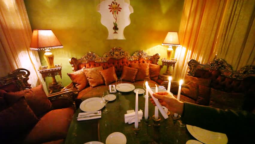 Man lights candles on decorated table among subjects of east decor
