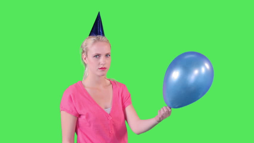 Female putting needle in balloon and popping it on greenscreen