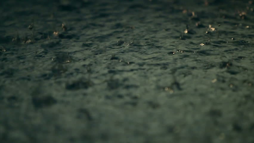 Drops of rain on a puddle in the evening