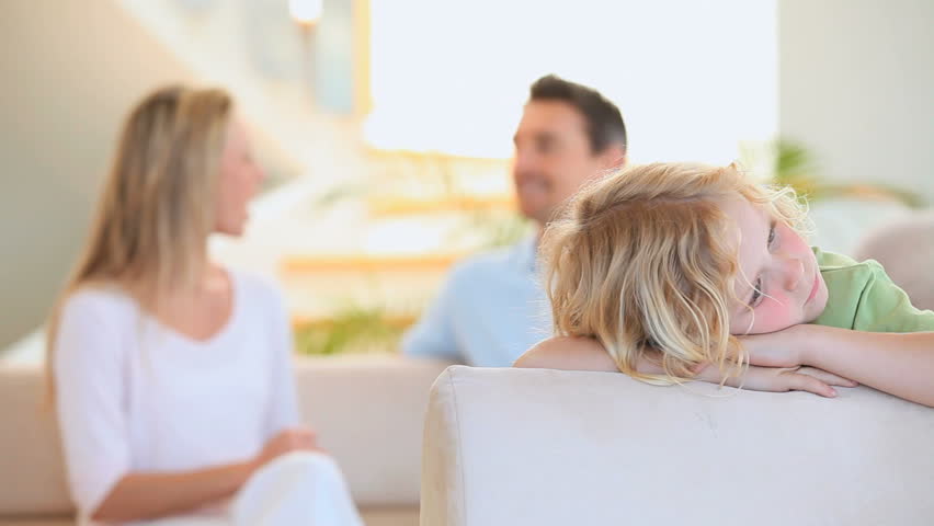 Sad blond boy hearing his parents arguing in the living room