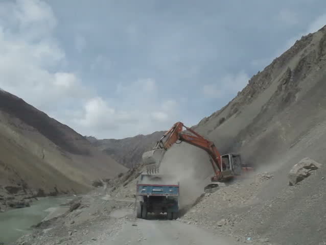 Excavator and Truck moving rock and sand to clear the road from Ladakh to Srinagar, Jammu and Kashmir state - India