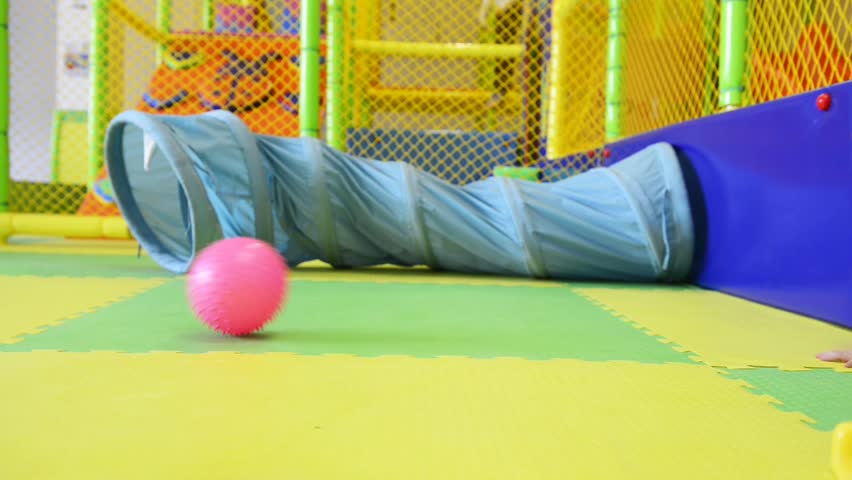 Small baby crawls, following pink ball. tracking shot. 
