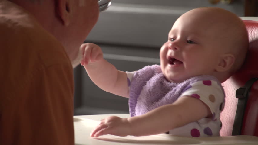 Grandfather talking with his granddaughter in high chair