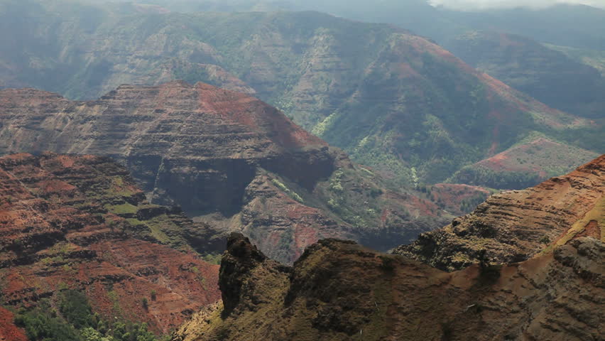 elevated view of a tropical canyon with reddish soil and green growth