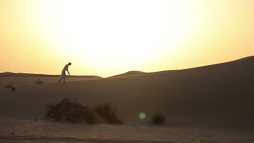 Weary man goes in the desert at sunset