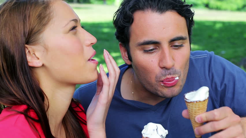 Smiling couple eating cones in a parkland