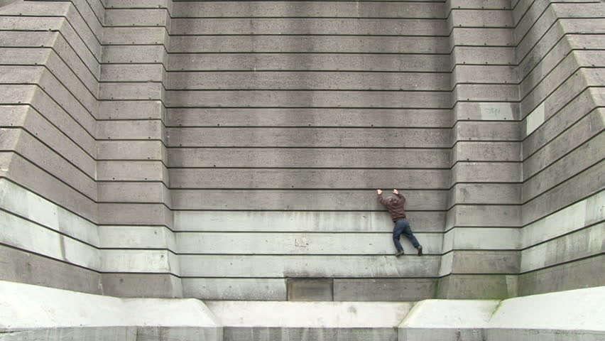 Man scales concrete wall and travels across carefully, time lapse.