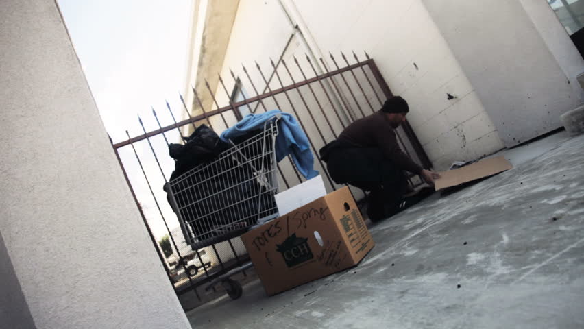 Homeless man preparing a place to sleep in an alley