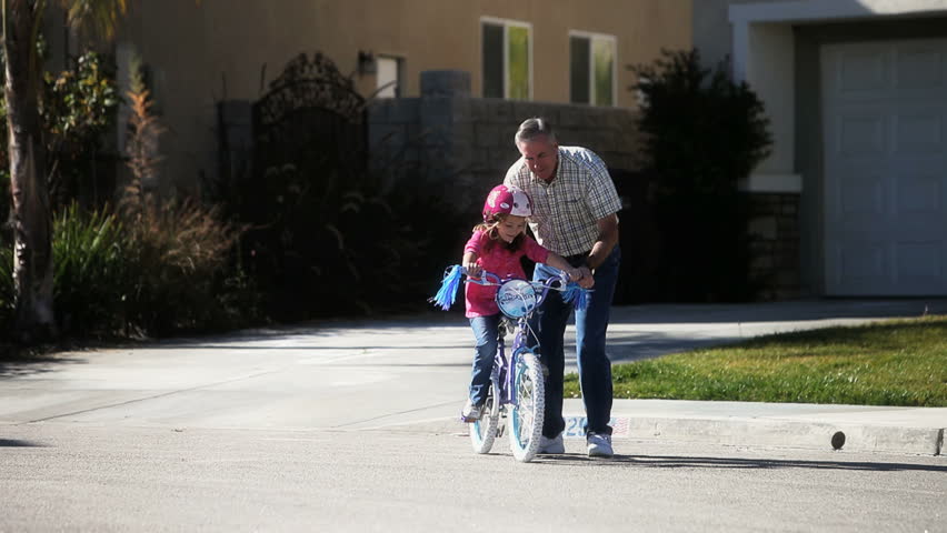 Father teaching daughter to ride a bike