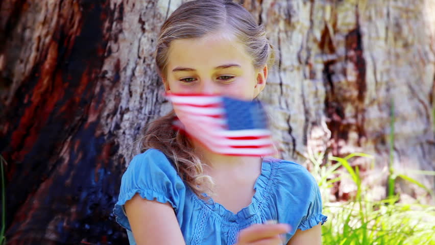 Girl playing with an american flag in a park